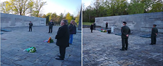 Wreaths and flowers are laid on the ground. People stand apart in a concrete quad as part of the 75th anniversary commemoration ceremony.