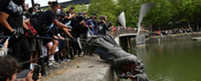 A photograph of protesters pushing the statue of Edward Colston into the waters of the nearby harbour in Bristol