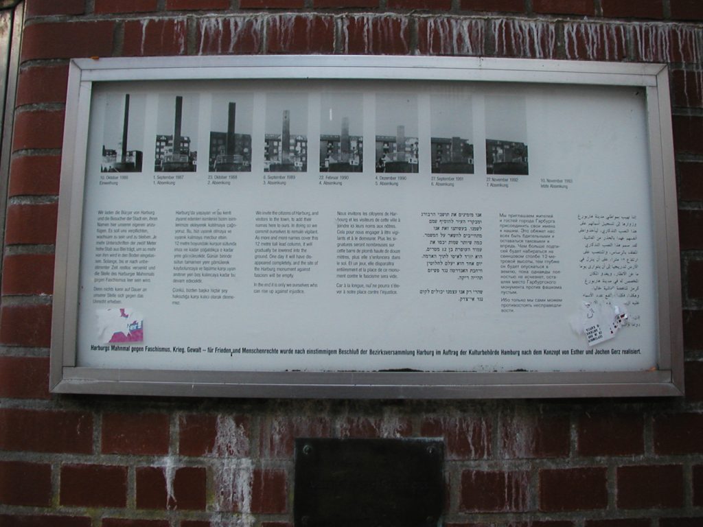 Framed poster on brick wall showing photographs of Harburg’s Monument against Fascism over time from 1986-1993 with text below each image 