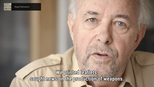 Gameplay. A film still of a man with greying hair and goatee. Text bottom of screen reads: We printed leaflets, sought news on the production of weapons. Top left a banner shows a thumbnail of an archival document with the text: illegal pubications.