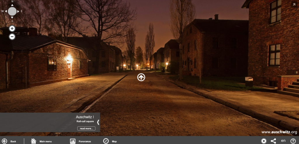 'Virtual tour' screenshot. Tag says' Auschwitz I: Roll Call Square'. Image - sunshine over brick barracks.