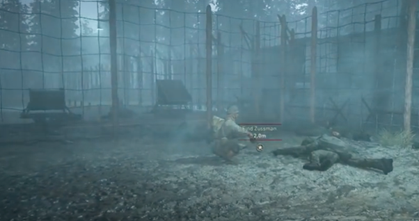 Computer game: a soldier crouches down next to a seemingly dead body surrounded by fences.