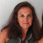 A woman with long brown hair smiles at the camera.