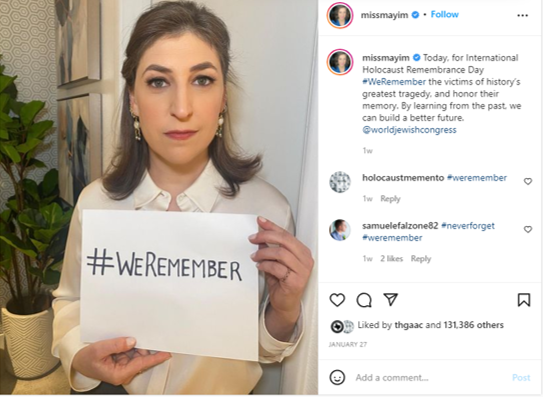 Instagram screenshot: Miss Mayim. With neat hair and makeup, wearing a white blouse, she holds up a sign saying hashtag we remember.