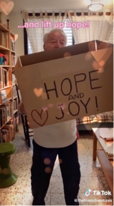 TikTok screenshot: An elderly gentleman holds up a cardboard box. Written on it are the words 'Hope and Joy'.