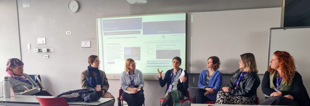 7 women in casual dress talk in front of a powerpoint.