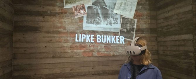 A woman with blonde hair wears a VR headset. She sits in front of a projection of historical photographs and the text 'Lipke Bunker'