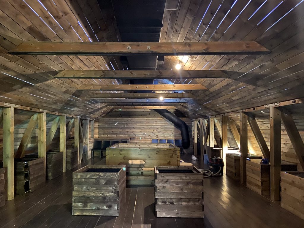 A wooden attic with wooden display cabinets spread around - the contents of which cannot be seen.